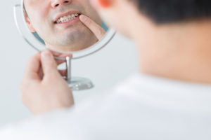 鏡を見て歯をチェックする男性